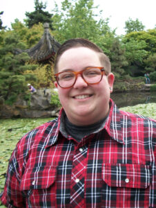 Profile photo of Ariel Leutheusser standing in front of a pond filled with lily pads with trees in the background